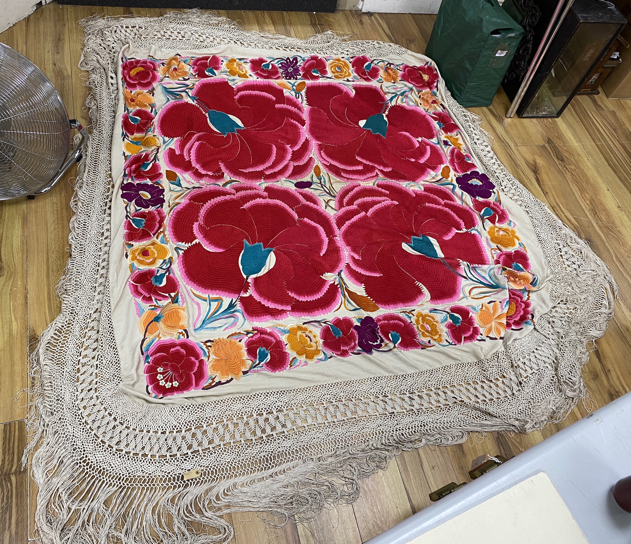 An unusual late 19th early 20th century Chinese cream silk shawl, embroidered with four huge bright pink and red flowers, surrounded with an embroidered floral border, all edged with a long cream silk tasselled fringe, 1